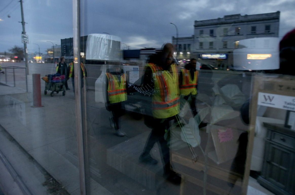Volunteers are reflected in the window of a discount furniture shop on Main Street.