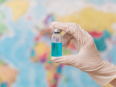 Doctor holds an ampoule with a vaccine on the back.