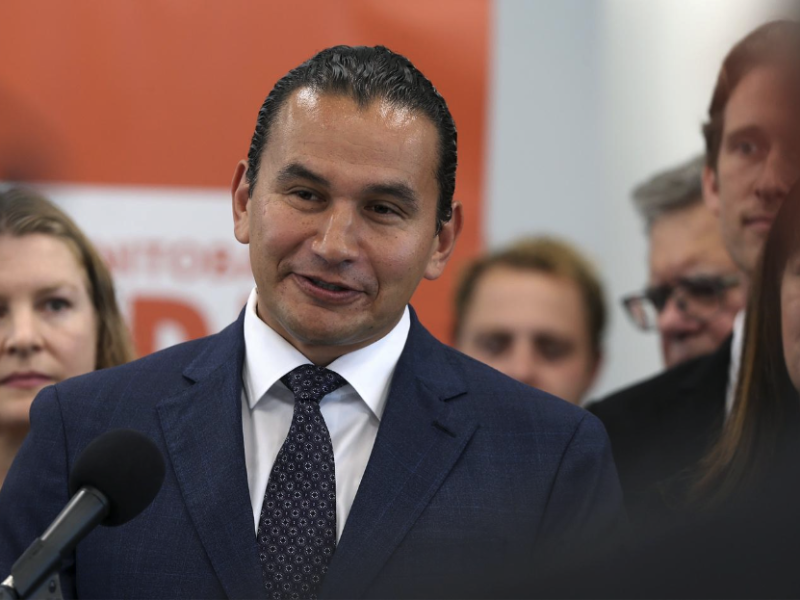 Wab Kinew stands at a podium and speaks to reporters shortly before becoming Manitoba’s 25th premier.