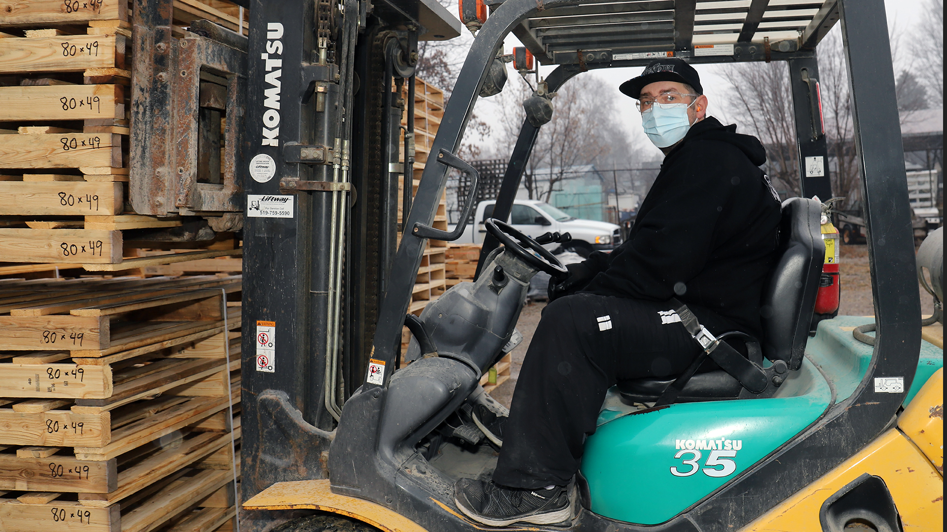 Stephen stacks pallets at the pallet shop.