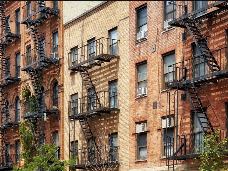 Yellow brick apartment buildings with black steel fire escapes.