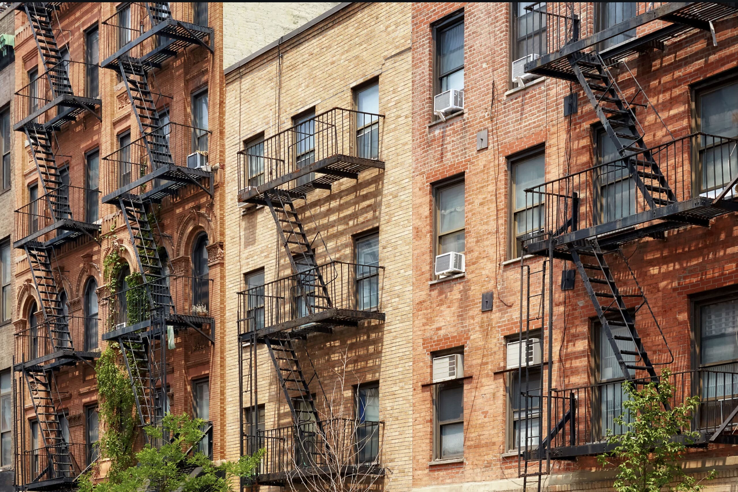 Yellow brick apartment buildings with black steel fire escapes.
