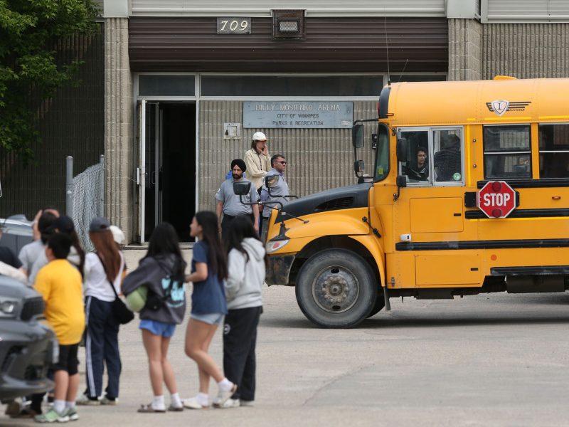 Wildfire evacuees at a Red Cross centre in Winnipeg. Youth are arriving by school bus at a brick arena.
