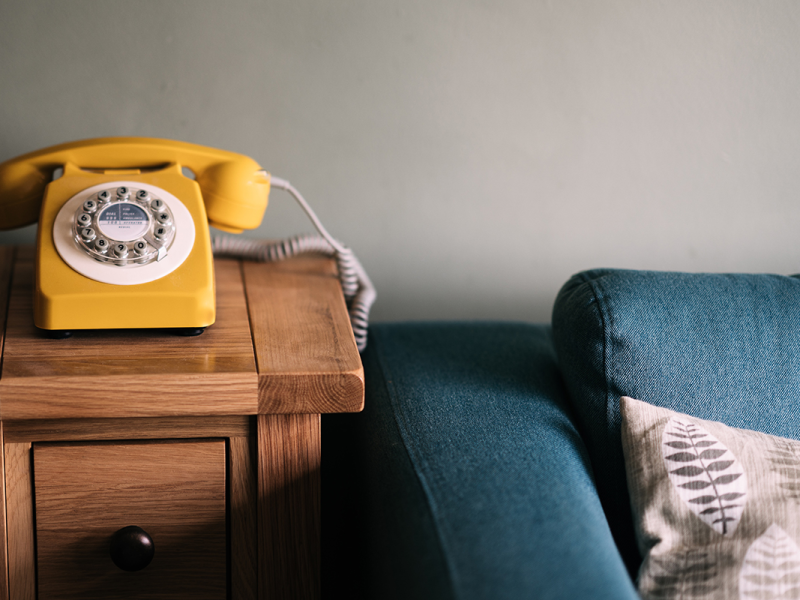 Yellow Phone on side table next to a couch illustrating increasing service demand for children's mental health organizations like Kids Help Phone